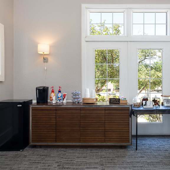 a bar in a room with large windows and a table with drinks on it