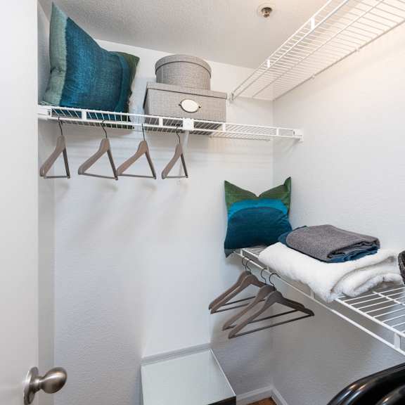a laundry room with a chair and a shelf with towels on it