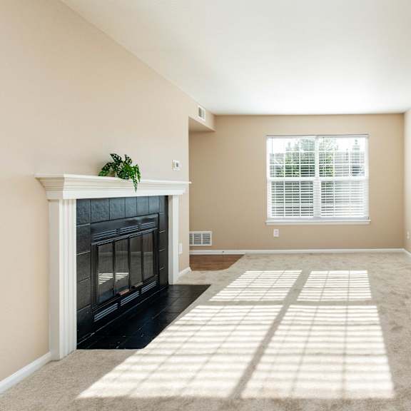 an empty living room with a fireplace and a window