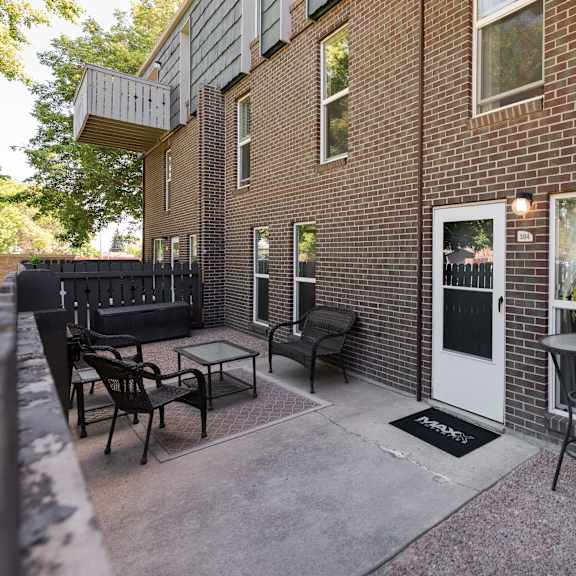 a patio with chairs and a table outside of a brick building