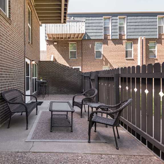 a patio with chairs and a table outside of a brick building