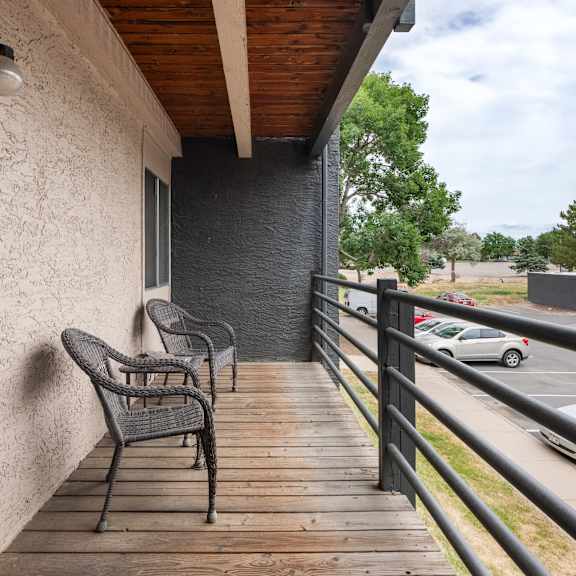 a balcony with two chairs and a building with a parking lot