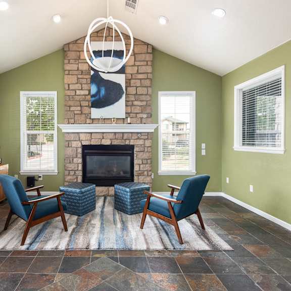 the living room has a large stone fireplace and blue chairs