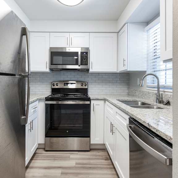 a modern kitchen with a stainless steel refrigerator and white cabinets.