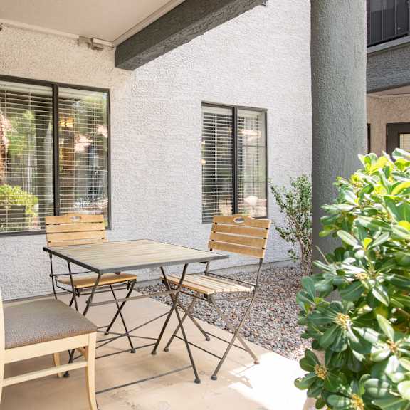 a patio with a table and chairs outside of a house
