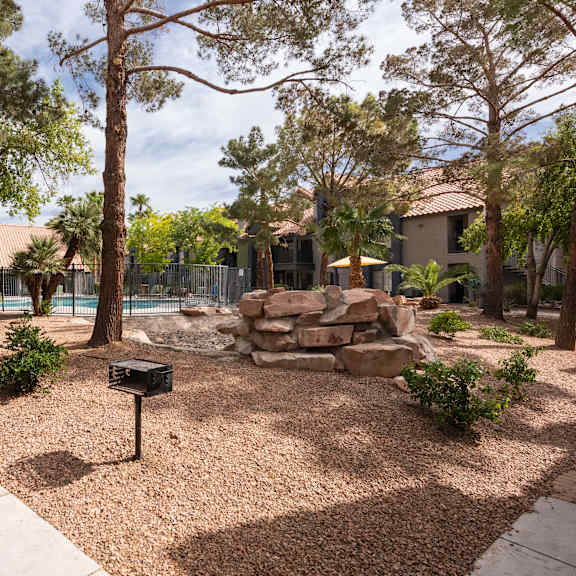 a backyard with a pool and trees and a sidewalk