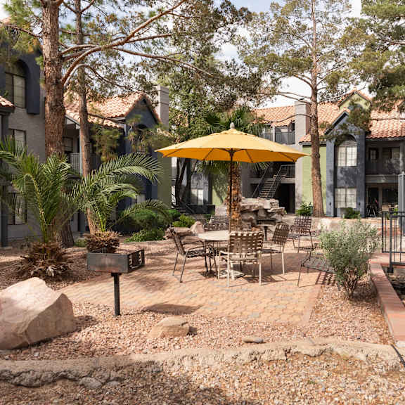 a patio with tables and an umbrella in a courtyard
