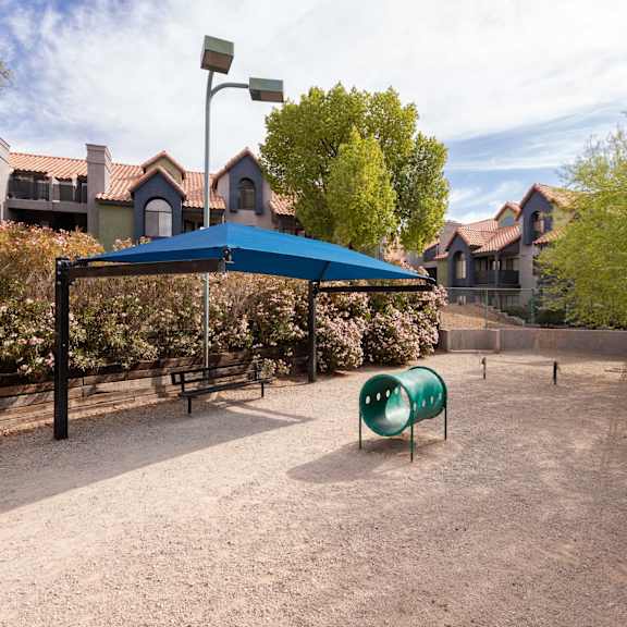 a playground with a blue tent and a green chair     and houses