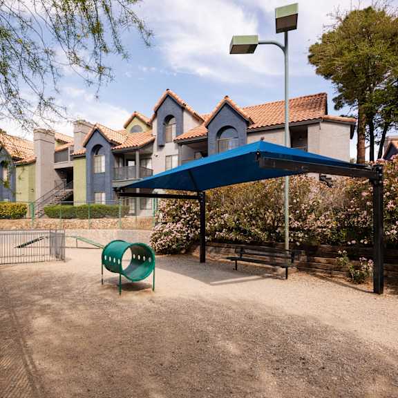 a park with a playground and a blue canopy
