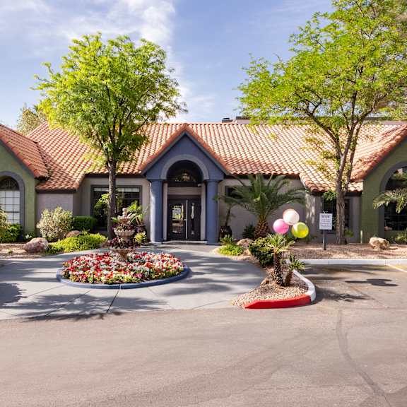 the front of a house with a driveway and trees and plants