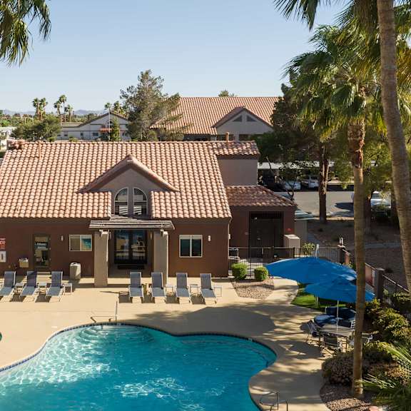 a house with a pool and chairs in front of it