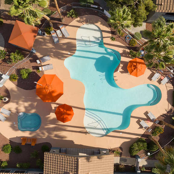 an overhead view of a swimming pool at a resort with umbrellas