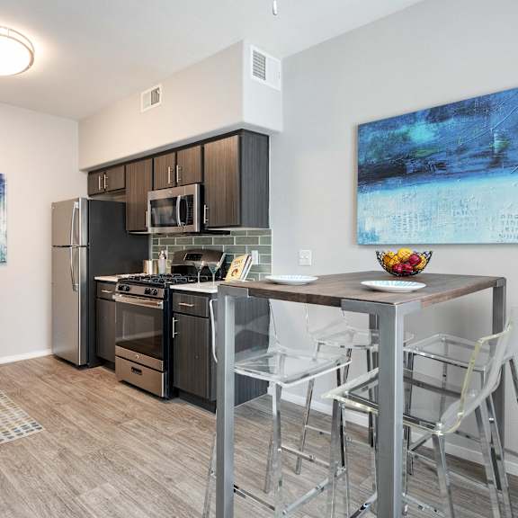 a kitchen with a bar with stools and a stainless steel refrigerator