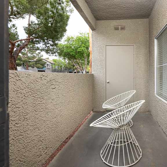 a patio with two chairs and a table in front of a door