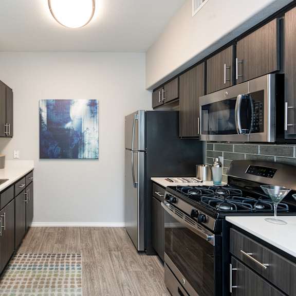 an empty kitchen with stainless steel appliances and wood flooring