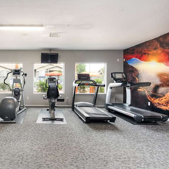 a gym with treadmills and other exercise equipment in a building with windows
