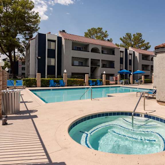 a swimming pool with a hot tub in front of an apartment building