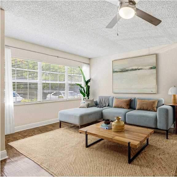 a living room with a grey couch, a wooden coffee table, and a painting on the wall.