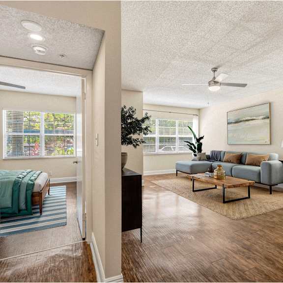 a living room with a couch, a coffee table, and a bed with a blue blanket.