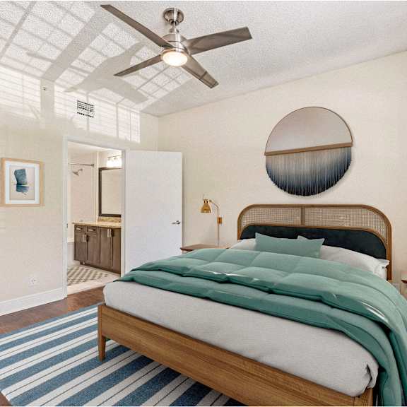 a bedroom with a bed, a ceiling fan, and a round mirror on the wall.