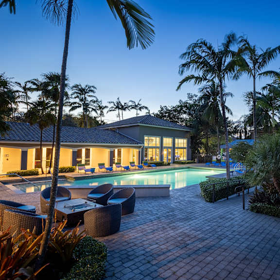a house with a pool surrounded by palm trees.