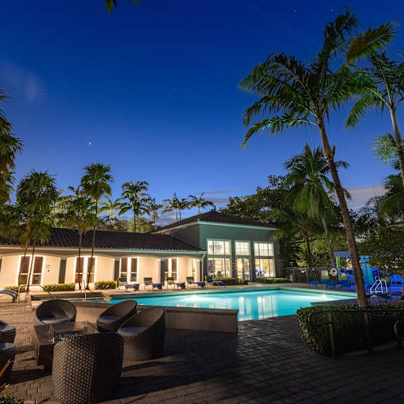 a pool surrounded by palm trees and lounge chairs.