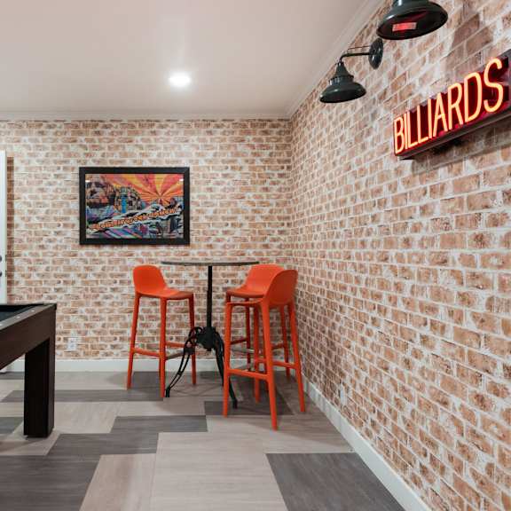 a game room with a pool table and orange chairs