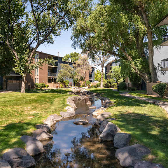 a stream runs through a grassy area between two apartment buildings