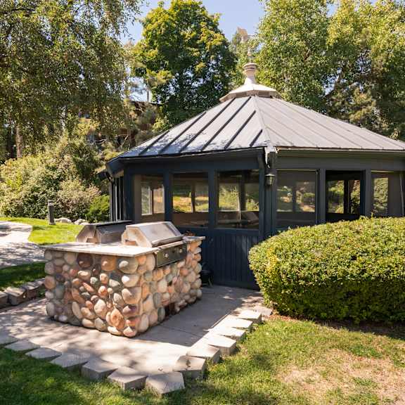 a gazebo in the backyard of a house with a stone fire pit