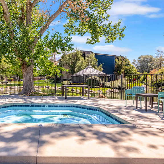a hot tub with trees and a fence around it