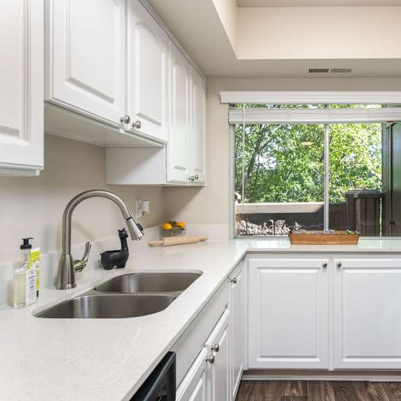 a kitchen with white cabinets and a sink and a window