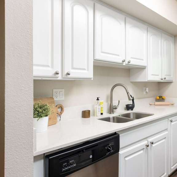 a kitchen with white cabinets and a sink and a window