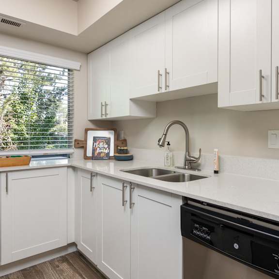 a kitchen with white cabinets and a sink and a window