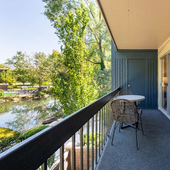 a balcony with a table and chairs and a river