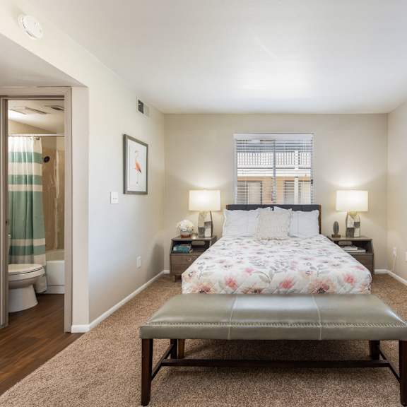 a bedroom with a bed and a stool in the middle