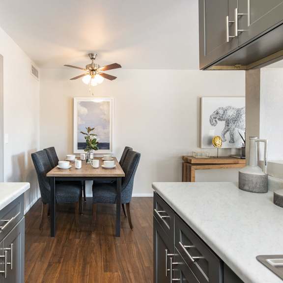 an open kitchen with a dining table and a ceiling fan