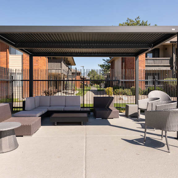a lounge area with couches and chairs under a shade