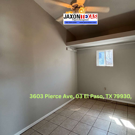 a room with a ceiling fan and a window, with a jaxon realty sign on the wall.