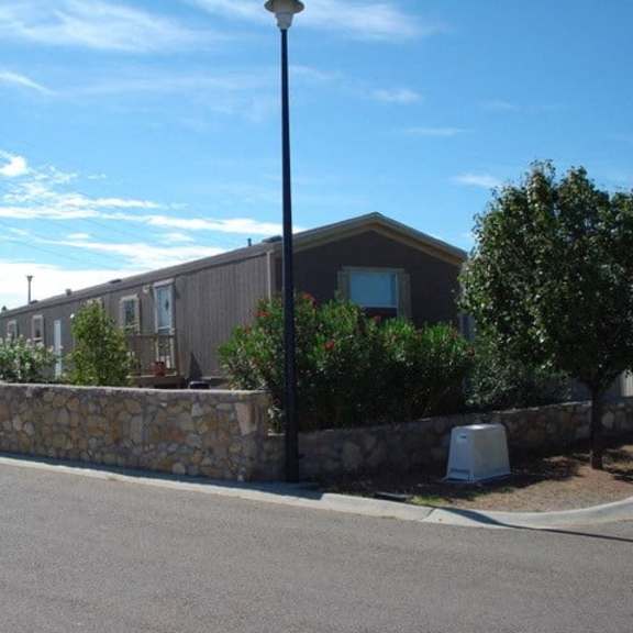 a street view with a house, a lamp post and a stone wall.