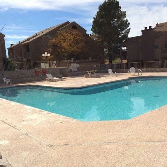 a swimming pool surrounded by a stone wall and a fence.