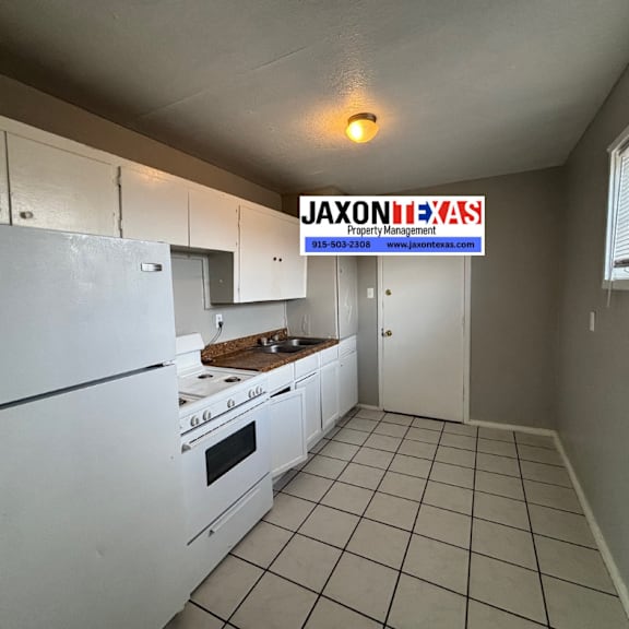 a kitchen with white appliances and cabinets with a jaxon b.a.s.s property management sign in the background.