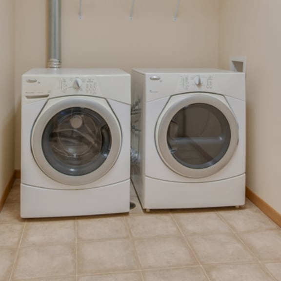 two white front loading washing machines in a laundry room.