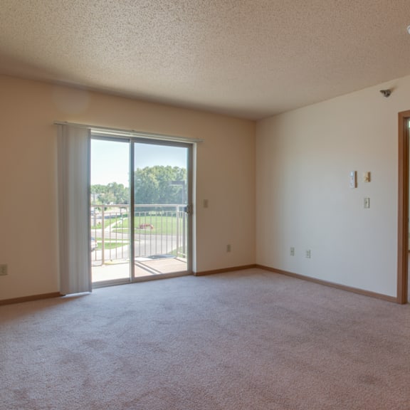 a room with a carpeted floor, a sliding glass door, and a mirror on the wall.