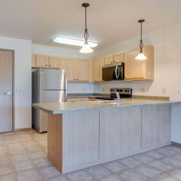 a kitchen with wooden cabinets and a stainless steel refrigerator.