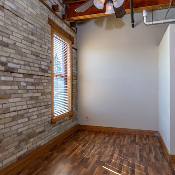 a room with a brick wall and wooden flooring.