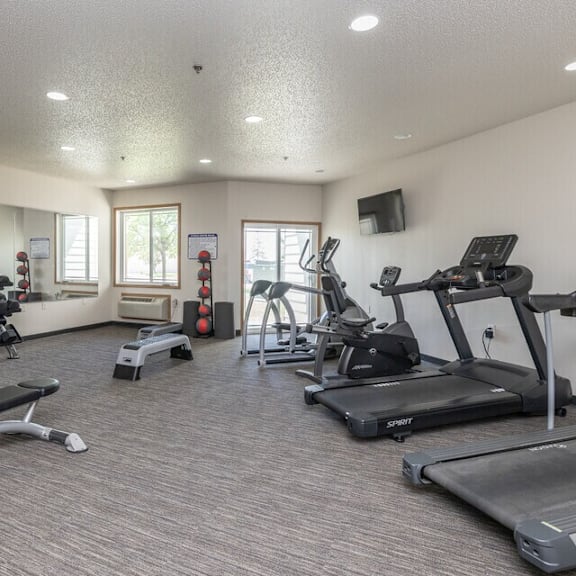 a spacious gym with a variety of equipment including treadmills, weights, and exercise machines.
