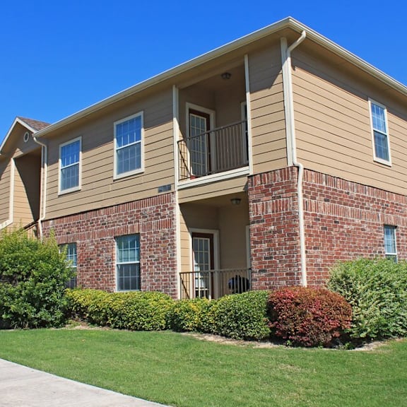 a two-story apartment building with a brick facade and a balcony on the second floor.