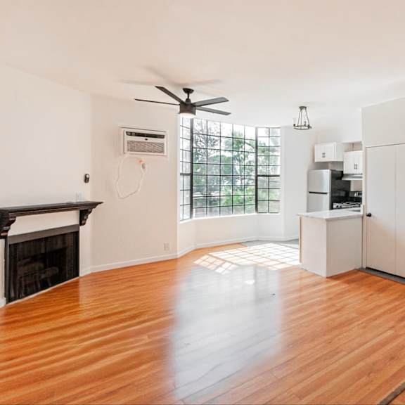 a spacious kitchen with white cabinets and a wooden floor.
