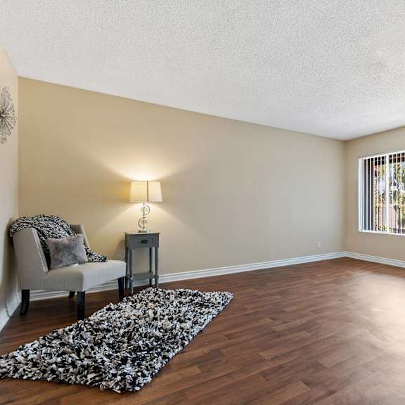 an empty living room with a chair and a rug at terramonte apartment homes, pomona, ca