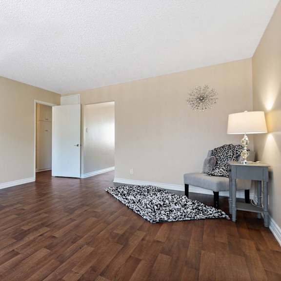 an empty living room with hard wood flooring and a chair and table at terramonte apartment homes, pomona, california